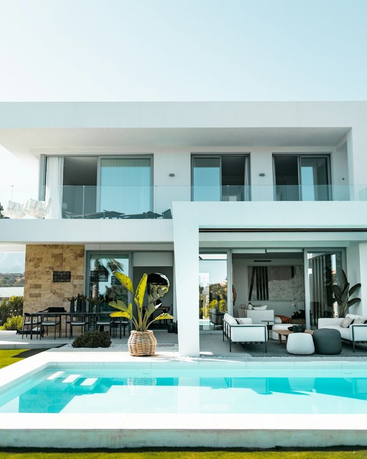 A modern white villa with a swimming pool and lounge area